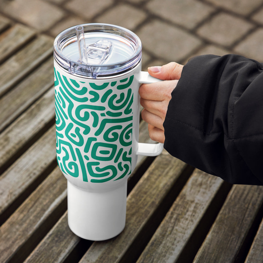 White tumbler with green pattern held by a person on a wooden surface
